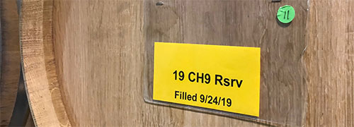 Yellow paper label with black lettering on a wood barrel background