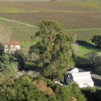 Aerial image of the white ranch house and white barn with vineyards in the distance