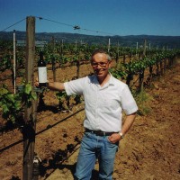 George Hendry, Owner stands next to vine with bottle