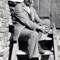 Black and white image of a distinguished man in a suit sitting on wooden stairs- George Whiting Hendry