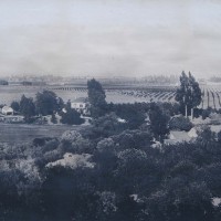 Grainy black and white photo of the white ranch house and barn, with trees, 1880s