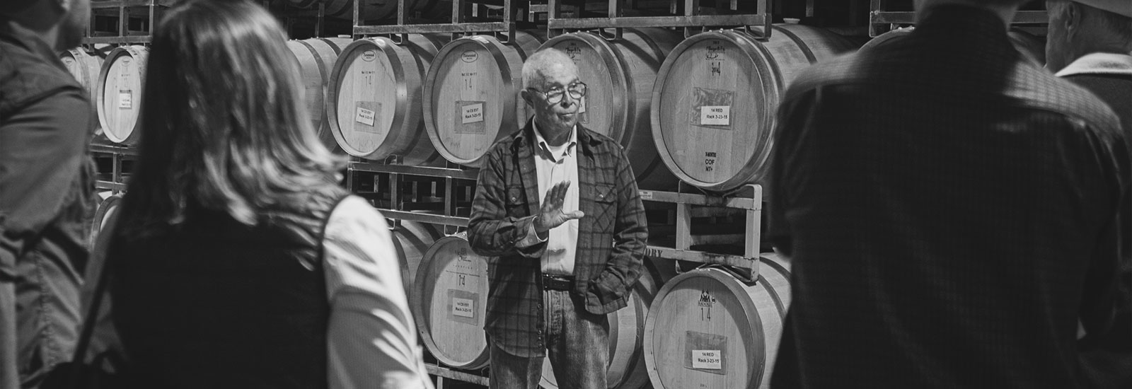 George Hendry conducting tour with stop in front of wine barrels